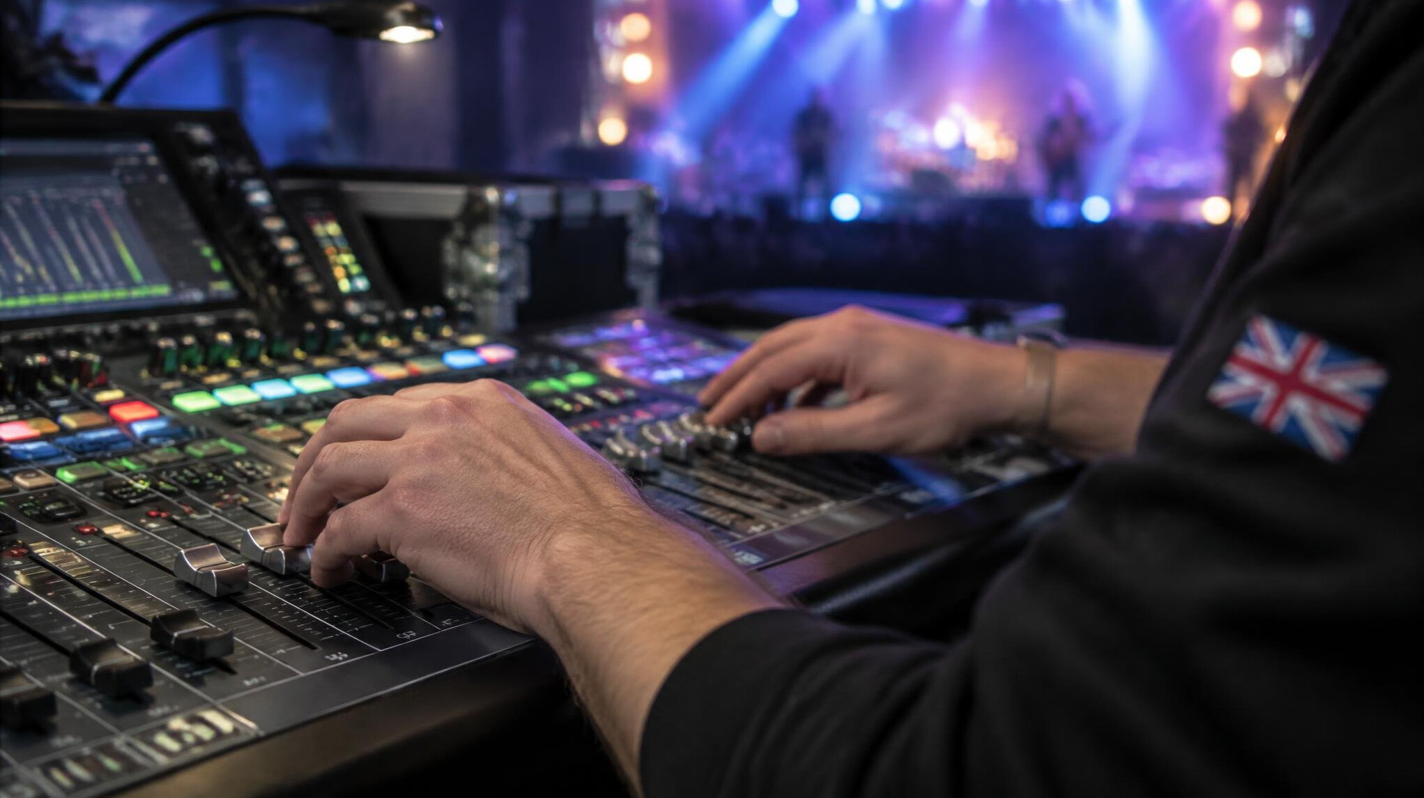 Close-up of hands adjusting faders on a live sound mixing desk
