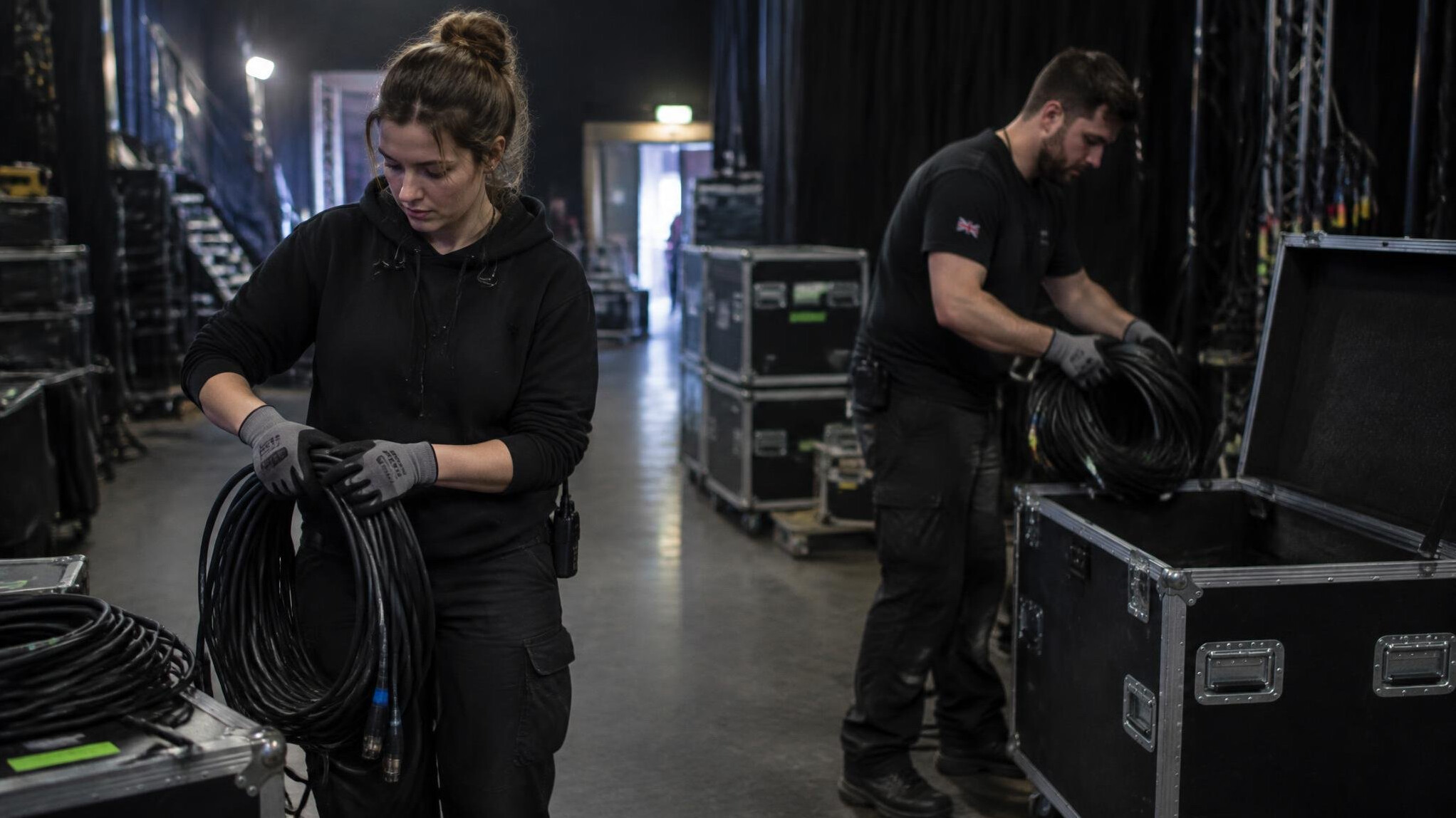 Production crew coiling cables backstage after an event